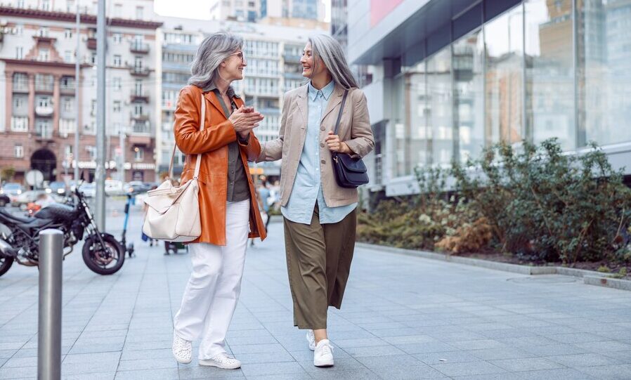 zwei Frauen laufen über einen breiten Gehweg und unterhalten sich