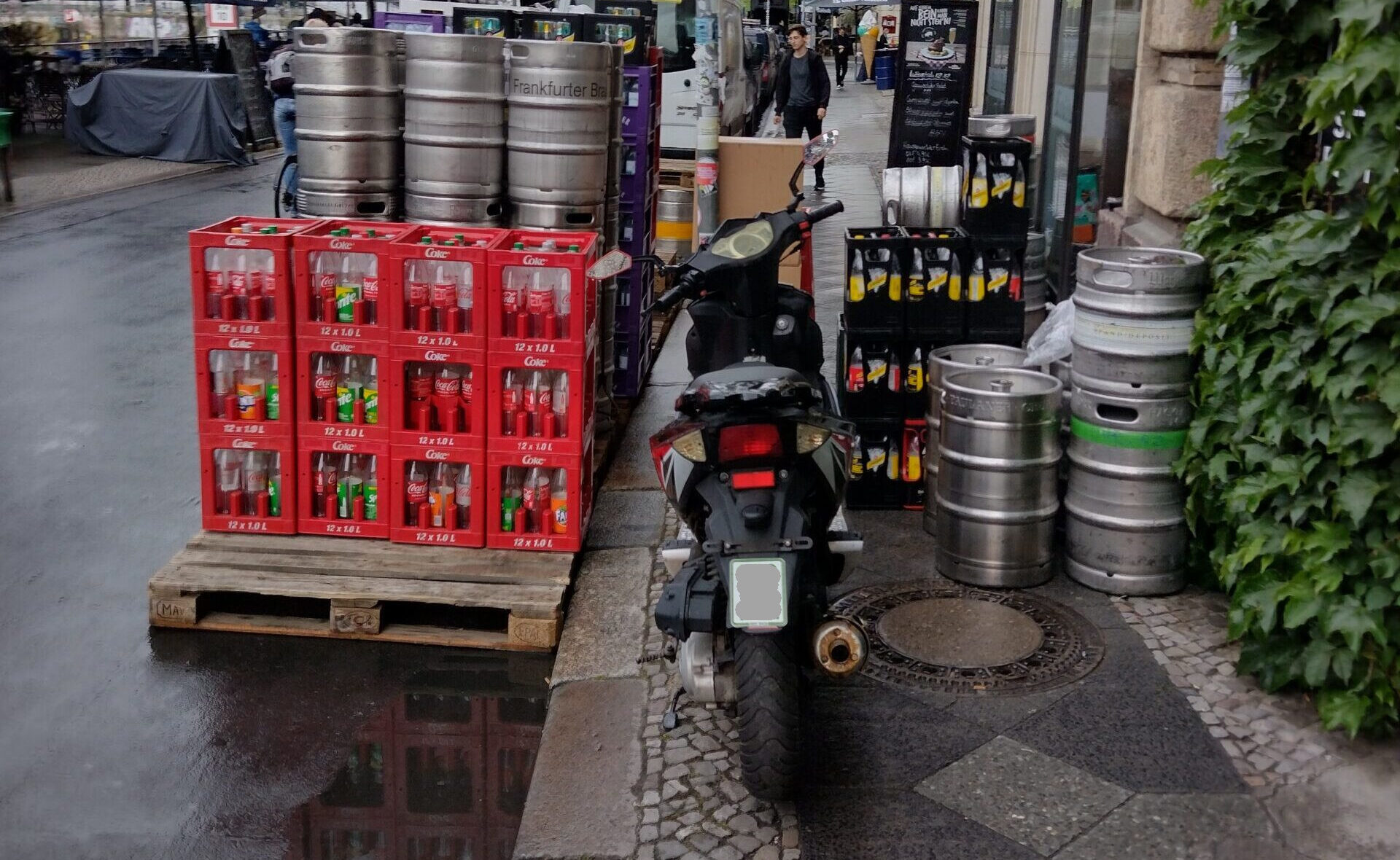 Bierfässer und Motorrad blockieren den Gehweg