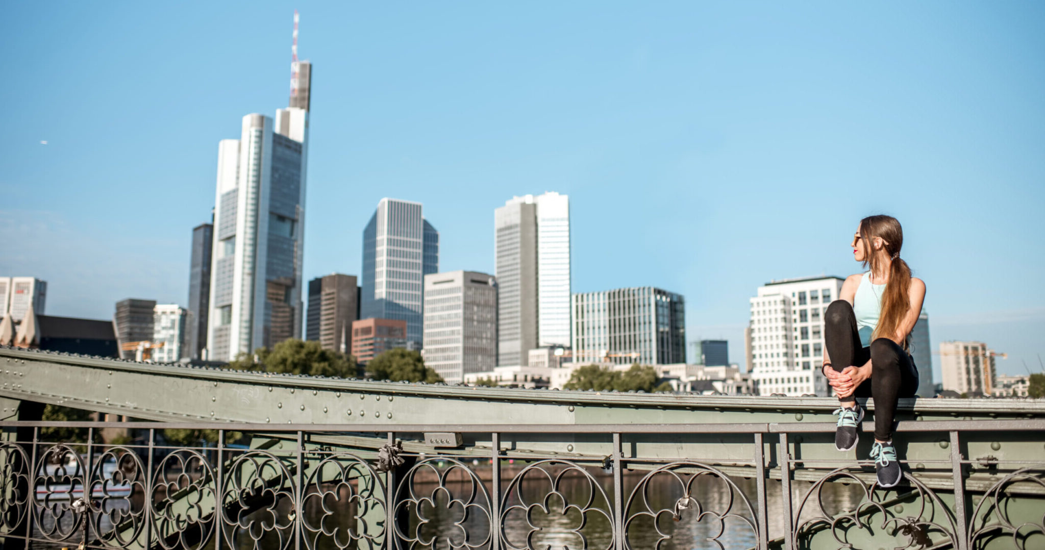 Junge Frau sitzt vor der Skyline von Frankfurt am Main