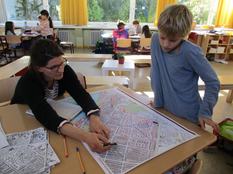 Lehrerin zeigt einem Schüler etwas auf einer Karte