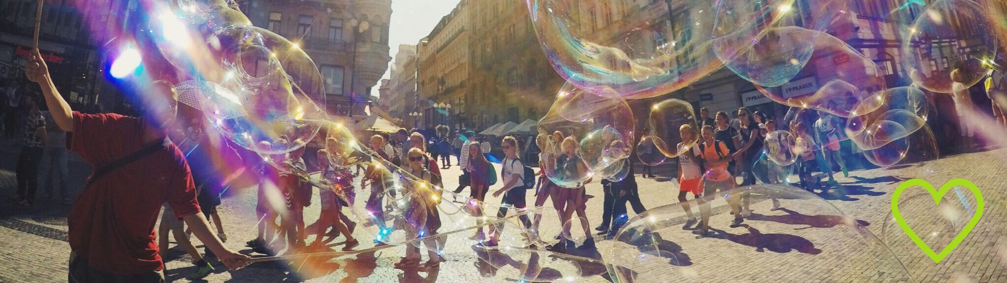 eine Gruppe Kinder läuft durch die Stadt, im Vordergund bunte Seifenblasen